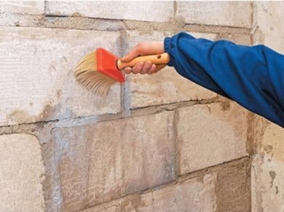 Грунтувати стіну потрібно широким пензлем або за допомогою пульверизатора